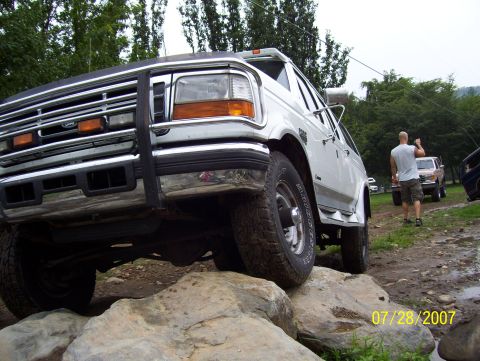 1978 Ford Bronco - A white Ford Bronco navigates a rocky terrain with other vehicles in the background.