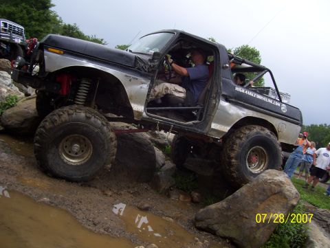 1978 Ford Bronco - This heavily modified SUV navigates a challenging rocky terrain, with spectators watching the action.