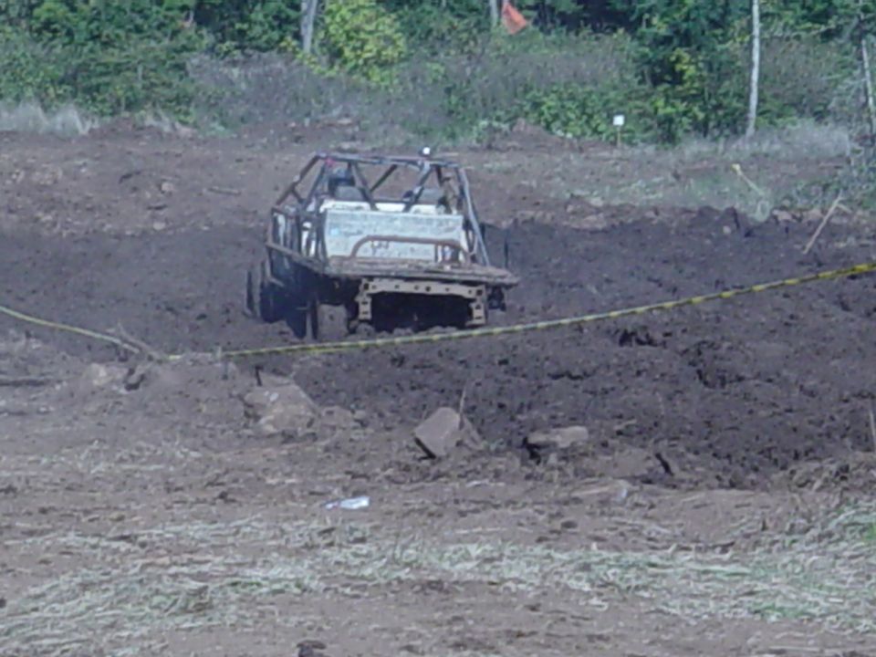 Tube-chassis rock buggy crawling through a muddy off-road pit