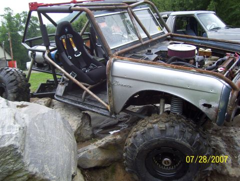 1978 Ford Bronco - Modified 1978 Ford Bronco with extensive roll cage and racing seats navigates rocky terrain, with another truck visible in the background.