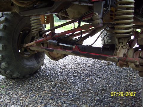 1978 Ford Bronco - A close-up view of the undercarriage reveals the complex suspension and steering systems of a vehicle, with prominent tires and red-painted…
