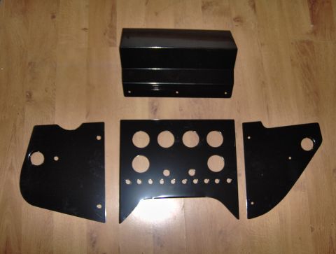 1978 Ford Bronco - Several black metal parts, possibly for a vehicle's center console, are laid out on a wood-grain surface.