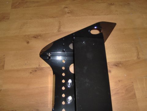 1978 Ford Bronco - A black metal bracket with various holes and mounting points is shown on a wooden surface.