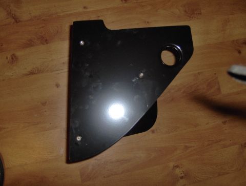 1978 Ford Bronco - A black metal component with a circular cutout rests on a wood-paneled surface.
