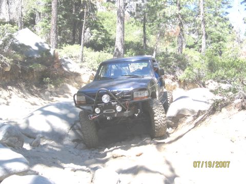 1994 Ford Bronco - Modified 1994 Ford Bronco tackling a challenging off-road path with large rocks.