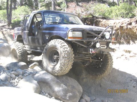 1994 Ford Bronco - Modified SUV navigates a rocky trail with large, aggressive tires.