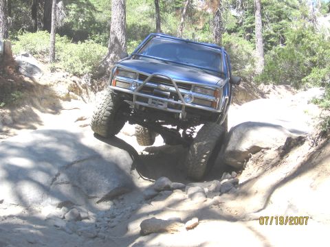 1994 Ford Bronco - This blue SUV is shown tackling a challenging rocky trail, demonstrating its off-road capabilities.