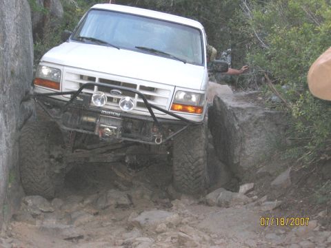 1994 Ford Bronco - A white 1994 Ford Bronco maneuvers through a challenging rocky terrain, demonstrating its off-road capabilities.