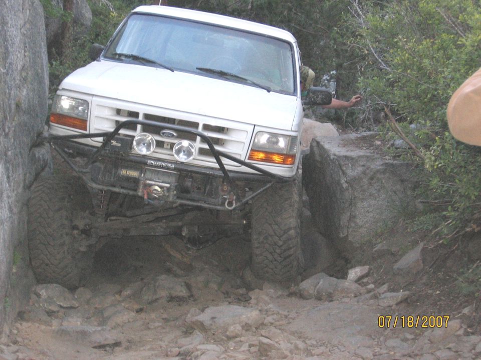 White Ford Bronco with winch bumper crawling over granite rocks on a trail
