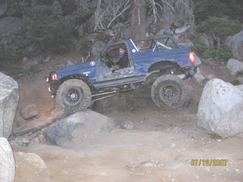 1994 Ford Bronco - A modified blue off-road vehicle tackles a challenging rocky trail.