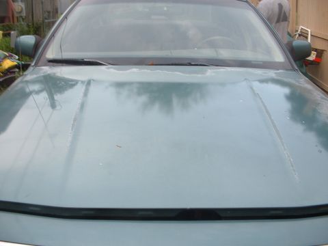 1993 Ford Crown Victoria - The front of a car is shown, focusing on the hood and windshield area. The paint appears faded.