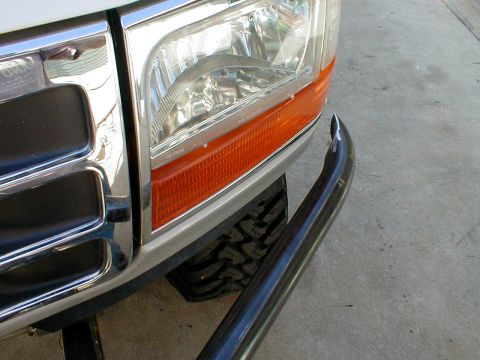 1996 Ford Bronco - A close-up view of a truck's front end, focusing on the headlight, grille, and a chrome bull bar.
