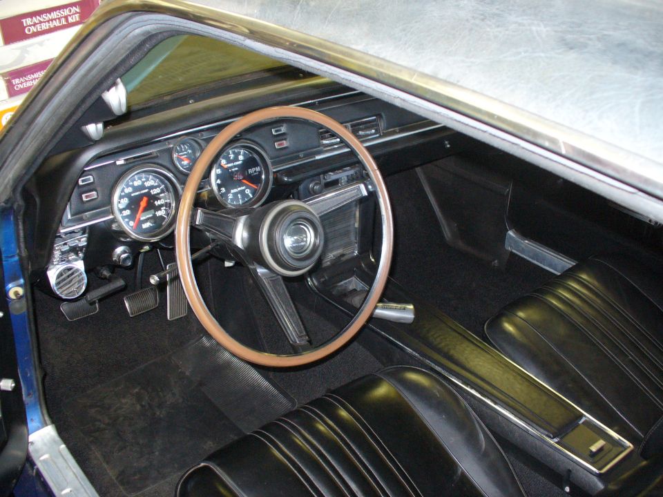 1968 Mercury Cougar interior with wood-rimmed steering wheel, dashboard gauges, and black vinyl seats