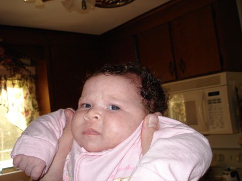 2000 Ford Crown Victoria - A baby with curly hair wears pink pajamas while being held.