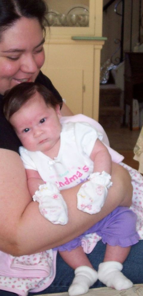 2000 Ford Crown Victoria - Woman holds a baby girl wearing a onesie that says 'Grandma's' and white mittens.