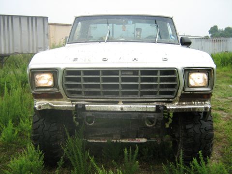 1990 Ford Bronco - This Ford truck, likely from the late 1970s, is parked in a grassy area with trailers in the background.