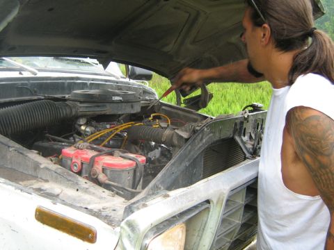 1990 Ford Bronco - A man works on the engine of a white truck, with the hood open and the engine compartment visible.
