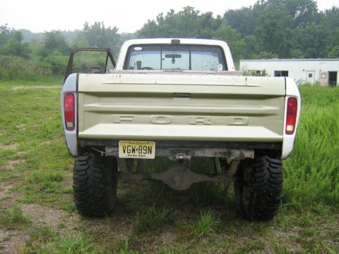 1990 Ford Bronco - This Ford pickup truck is shown from the rear with its driver's door ajar and large off-road tires.