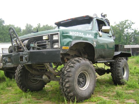1990 Ford Bronco - This heavily modified green truck, possibly from the 1980s, is equipped for off-road use with a winch and large tires.