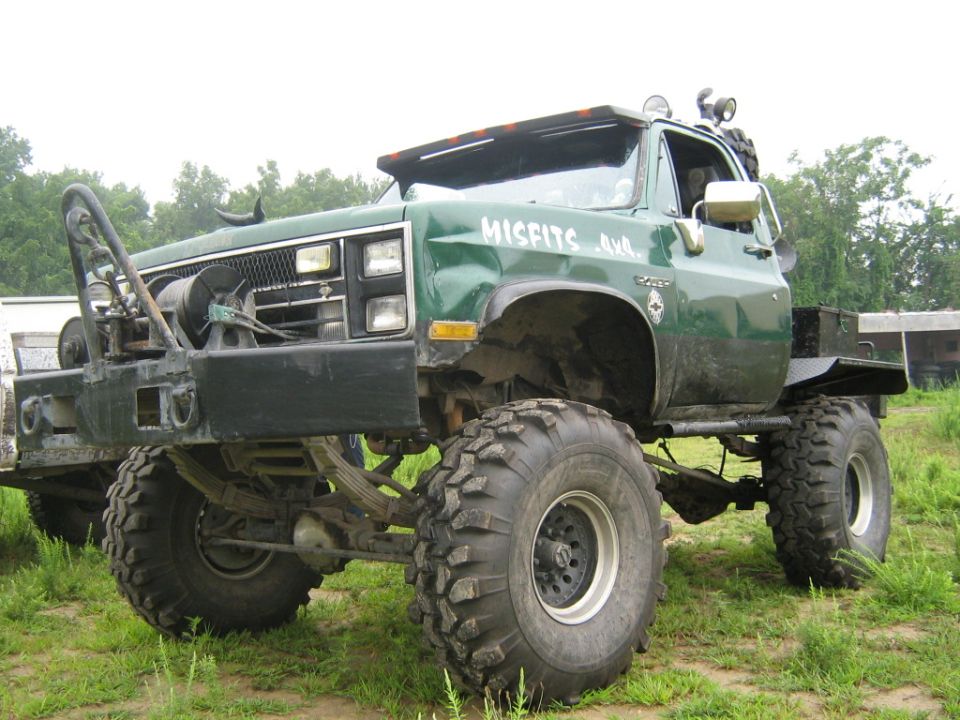 Green lifted truck with large off-road tires, winch, and "MISFITS 4x4" text on the door