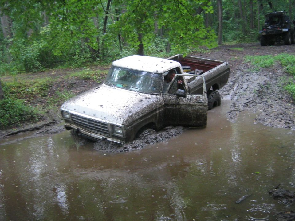 White Ford F-Series truck stuck in mud, driver's door open