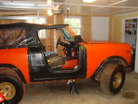 1994 Ford Bronco - An orange International Harvester Scout II is shown in a garage, with its doors removed and sitting on jack stands.