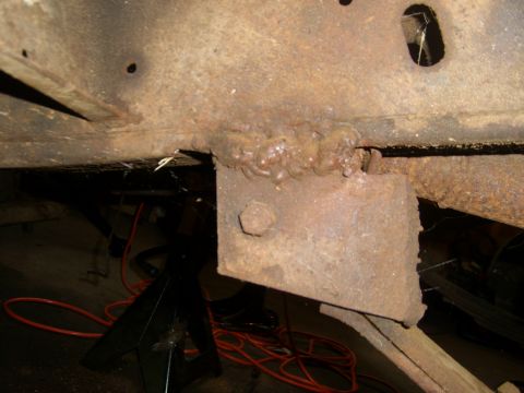 1994 Ford Bronco - Close-up of a heavily rusted frame bracket with a bolt and visible welding marks.
