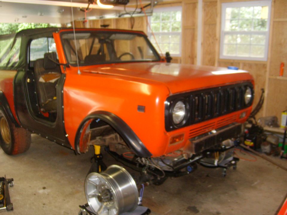 Orange and black SUV, front 3/4 view, soft top removed, in garage