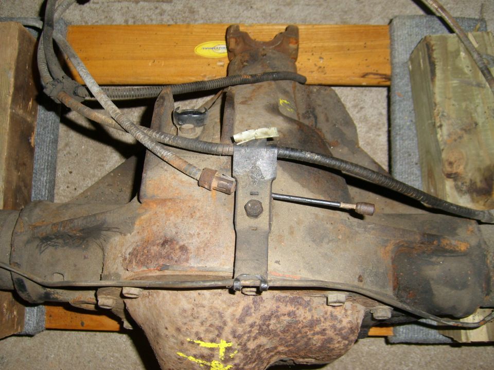 Rear axle assembly on wooden supports, showing brake lines and suspension components