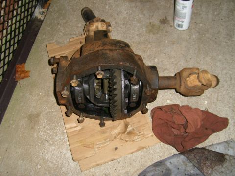 1994 Ford Bronco - A disassembled differential axle sits on a concrete floor next to a red rag.