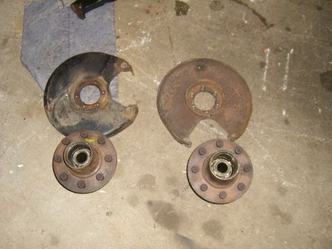 1994 Ford Bronco - Two brake rotors and their corresponding hubs are shown on a concrete surface, likely for a vehicle repair or parts sale.