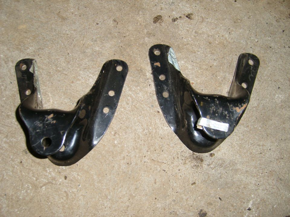 Two black metal leaf spring brackets on a concrete surface