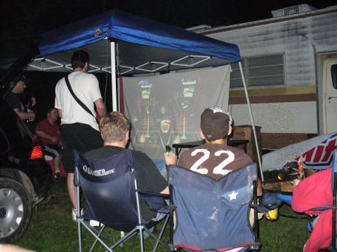 1991 Ford Probe - An outdoor gathering features a projected image, chairs, and a trailer, creating a casual evening scene.