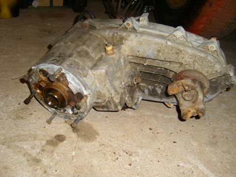 1994 Ford Bronco - A used transfer case sits on a concrete floor, awaiting installation or repair.