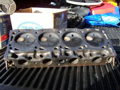 1979 Ford Bronco - Engine cylinder head part shown on a truck bed with other engine components in the background.