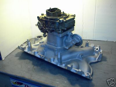 1979 Ford Bronco - Ford carburetor and intake manifold assembly shown on a workbench.