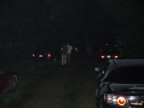 1991 Ford Probe - A nighttime scene shows multiple vehicles and individuals gathered outdoors.