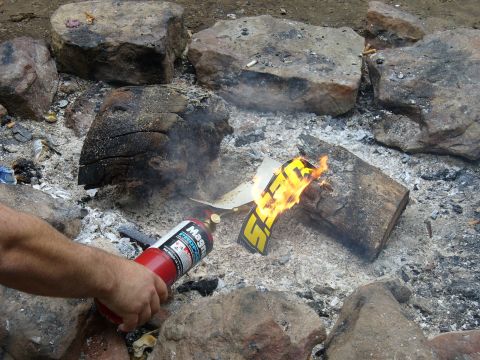 1991 Ford Probe - A car emblem is being burned in a fire pit, with a fire extinguisher nearby.