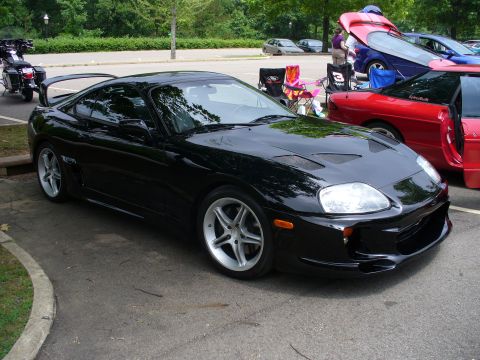 1991 Ford Probe - A black sports car with a prominent rear spoiler and custom hood vents is parked next to other vehicles.