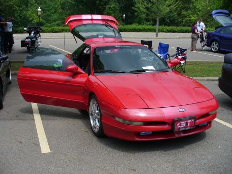 1991 Ford Probe - A red 1991 Ford Probe is parked with its doors and trunk open, showing off its interior and engine bay.