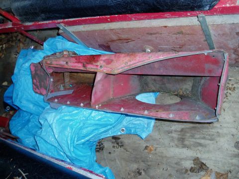 2000 Ford E350 - Unidentified red metal part, likely from a vehicle, covered partially by a blue tarp.