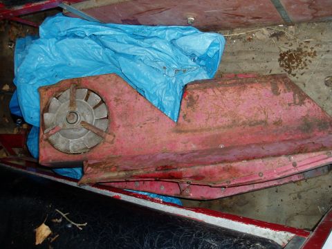2000 Ford E350 - A close-up of a rusty red automotive part with a fan, partially obscured by a blue tarp.