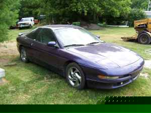 1996 Ford Probe - A purple coupe sits in a grassy area with trees and other vehicles visible in the background.