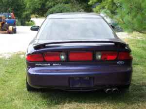 1996 Ford Probe - Rear view of a purple 1996 Ford Probe, showing its taillights, spoiler, and a visible "SUPERMOTORS" watermark.