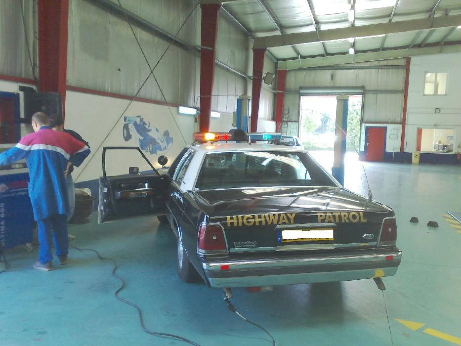 Black Ford Crown Victoria Highway Patrol car with light bar inside a garage