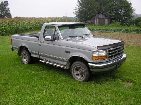 1994 Ford Probe - A silver Ford F-150 pickup truck is parked on a grassy area with a cornfield and a wooden barn in the background.