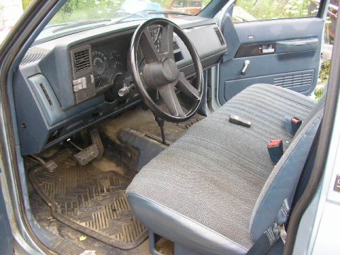 1994 Ford Probe - The interior of a light blue truck features a blue dashboard, steering wheel, and patterned cloth seats with seatbelts.