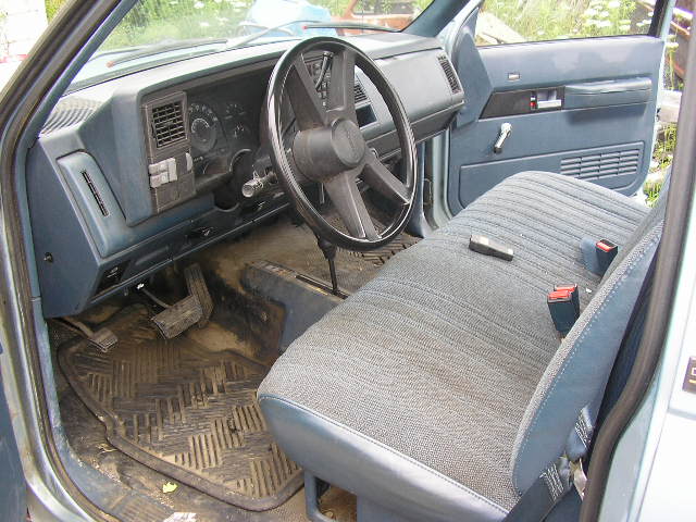 Interior of a light blue truck showing the dashboard, steering wheel, and seat