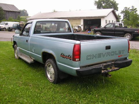 1994 Ford Probe - Rear view of a light blue Chevrolet pickup truck with 'CHEVROLET' and '4x4' badging, parked outdoors.