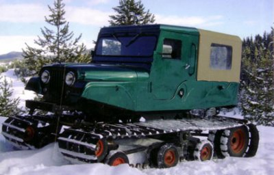 2000 Ford E350 - This unique vehicle is equipped with tracks for traversing snowy terrain, a green body and a tan soft top enclosure.